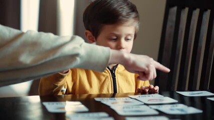 little boy learns words from cards under the ABA therapy program at home at the table