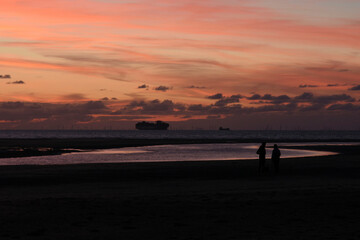 silhouettes of couple and boats on sunset beach Cadzand