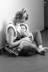 mom breastfeeds the baby, baby sucks breast milk in mom's arms, lifestyle, breastfeeding, black and...