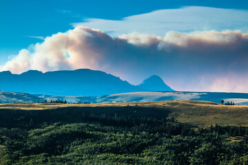 Obraz na płótnie Canvas A dramatic huge clouds of smoke billowing into the sky during a summer forest fire in Reynolds Creek in St.Mary's Lake in Glacier National Park in Montana. 