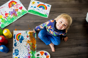 Sweet toddler blond child, boy, painting with colors, making finger prints