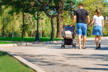 Obraz premium people walking and children playing in a city park on a summer day, green lawns with grass and trees, paths and benches, bright sunlight and shadows