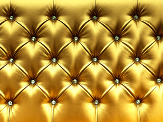 Stylish gold soft leather upholstery of sofa. The material is decorated with buttons in the form of crystals. Upholstery leather pattern background.