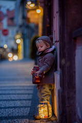 Obraz premium Sweet toddler boy, playing guitar at night in the city with teddy bear toy