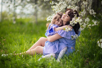 Fototapeta premium happy mom and daughter in the spring blooming garden playing together