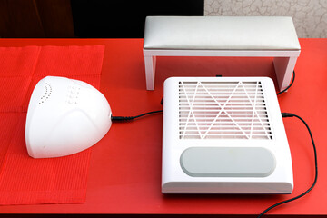 workstation of a nail manicure master. Professional equipment for manicure is on the red table.