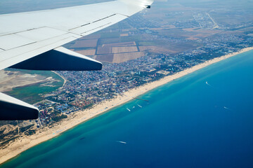 airplane wing from a porthole in flight over the sea