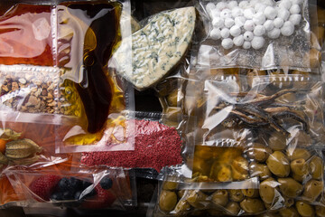 Different vegetables, fruits and cheese in plastic vacuum sealed bags