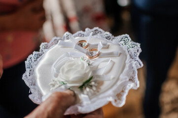 Wedding rings on a white pillow in hands