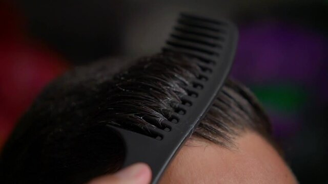 Man combs his hair with comb