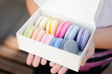 Multicolored sweet macarons or macaroon flavored cookies in a paper box