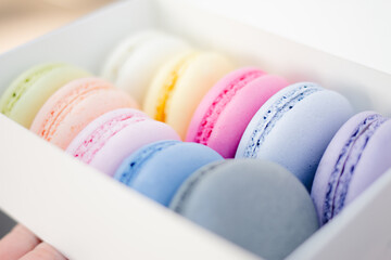 Multicolored sweet macarons or macaroon flavored cookies in a paper box