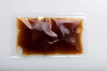 Brown sauce in vacuum sealed plastic bag on white background