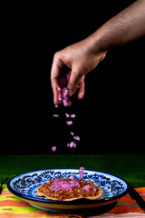 chef serving onion over the cochinita pibil tacos