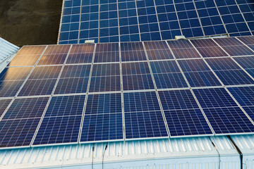 Aerial view of surface of blue photovoltaic solar panels mounted on building roof for producing clean ecological electricity. Production of renewable energy concept.