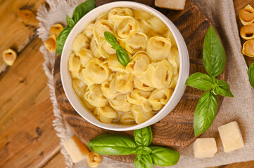Broth with Tortellini mignon with basil and parmesan. Specialties of the cuisine from Bologna and Emilia Romagna: Cappelletti, fresh egg pasta with meat and vegetables filling. 