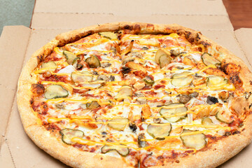 Close up of hot and fresh Pizza in the delivery box with cheese, mushroom, meat, pickles, pepperoni, mozzarella