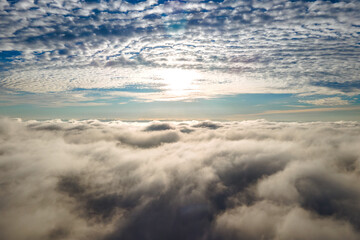 Aerial view from above of white puffy clouds in bright sunny day.