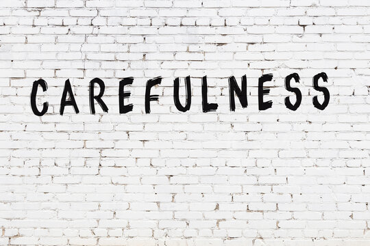 Inscription carefulness painted on white brick wall