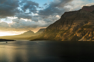 Fototapeta na wymiar dramatic golden summer sunrise in St Mary's lake in Glacier national park in Montana.