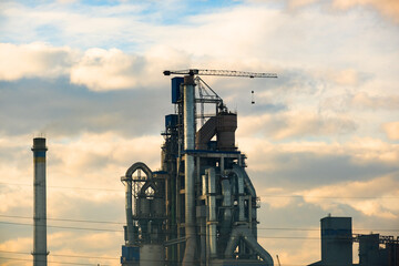 Cement plant with high factory structure and tower crane at industrial production area.