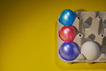 Pearl colored eggs in the egg tray on a yellow background.