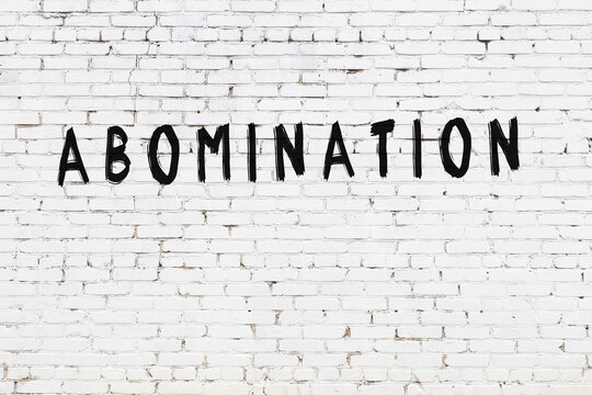 White wall with black paint inscription abomination on it