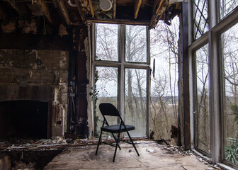 Empty chair looks out of a broken wall in an abandoned house.