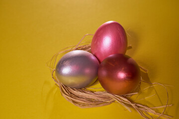 Pearl colored eggs in the nest on a yellow background.
