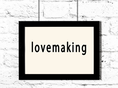 Black frame hanging on white brick wall with inscription lovemaking