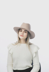 Fototapeta premium girl in a white sweater posing in a felt hat on a light background