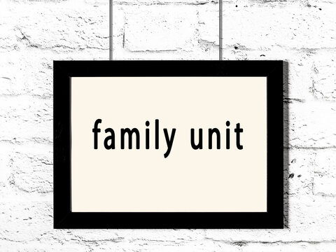 Black Frame Hanging On White Brick Wall With Inscription Family Unit