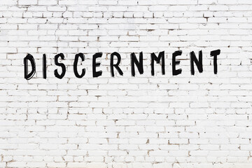 Inscription discernment painted on white brick wall