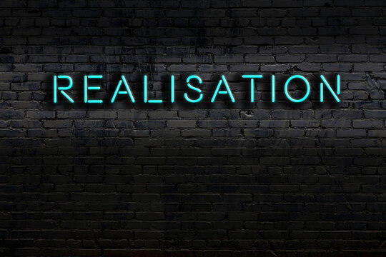 Night view of neon sign on brick wall with inscription realisation