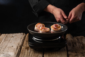 Chef prepares meat steaks in bacon, beef or pork. Chef on black background for restaurant menu text copy space