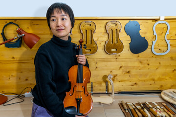 young Chinese violin maker at work in her workshop