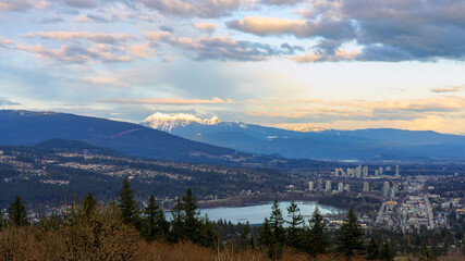 Rose-tinged clouds at dusk over Fraser Valley, Coquitlam and Port Moody, BC, with alpine mountains as backdrop and Burrard Inlet in foreground - late winter