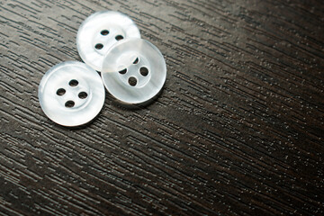 Some little white buttons on a black wooden table 