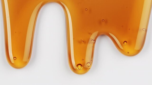 close up of flowing melted caramel sauce macro on white background