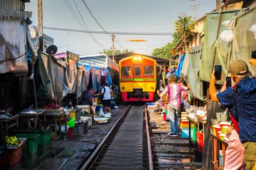 Fotobehang Train on Tracks Moving Slow. Umbrella Fresh Market on the Railroad Track, Mae Klong Train Station, Bangkok, Thailand on a Sunny Day. © kaycco