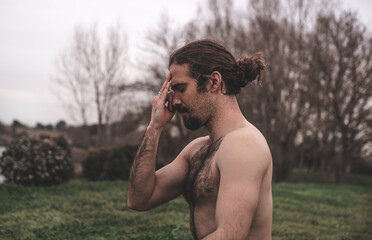 Young man stretching and relaxing on a yoga session in the park. Breathing technique, healthy,...