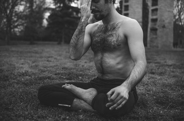 Young man stretching and relaxing on a yoga session in the park. Breathing technique, healthy,...