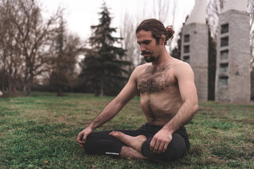 Fototapeta na wymiar Young man stretching and relaxing on a yoga session in the park. Breathing technique, healthy, fitness, contact with nature and wellness