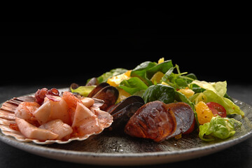 Seafood salad with pineapple and oranges on a plate, on a dark background