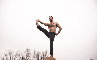 Young man stretching and relaxing on a yoga session in the park. Breathing technique, healthy,...