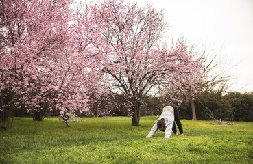 Young man stretching for a yoga session in the park. Fitness, healthy habits and wellness concepts.