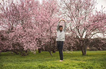 Young man stretching for a yoga session in the park. Fitness, healthy habits and wellness concepts.