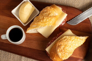 Baguette with cheese and salami served with a cup of coffee.