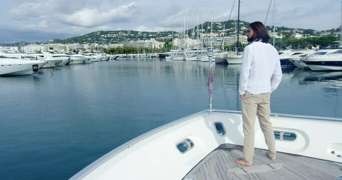 Man from behind standing on a boat sailing into the seagate, under the cloudy sky - Cinematic scene with RED Camera 4K H264