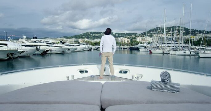 Handsome man from behind standing on a boat sailing into the seagate, under the cloudy sky - Cinematic scene with RED Camera 4K